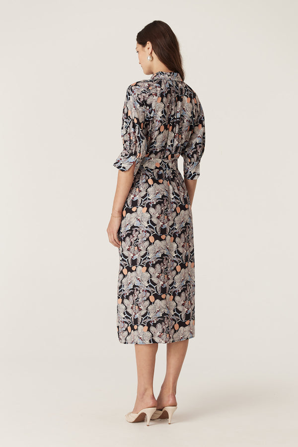 Woman in a black silk blend Leigh Midi Dress with an orchid print, button-through front, and elbow sleeves.