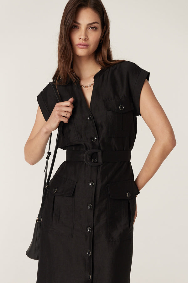 Woman in black linen-viscose Osborne dress with button front, utility pockets, and D-ring belt.