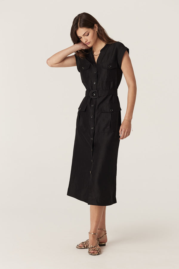 Model wears a black linen viscose Osborne dress with a cut-away collar, button front, utility pockets, and D-ring belt.