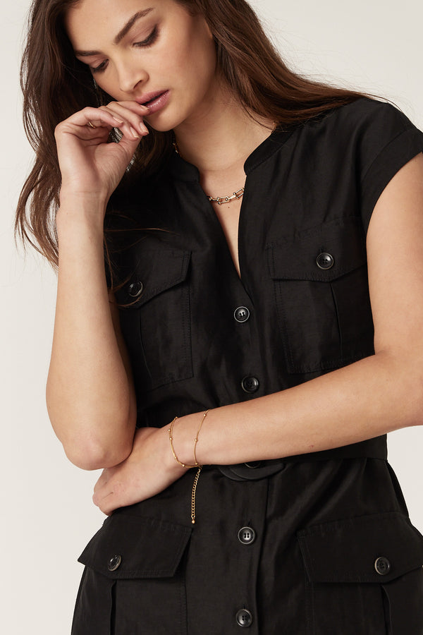 Woman in a black linen blend Osborne dress with button-through front, utility pockets, and D-ring belt.