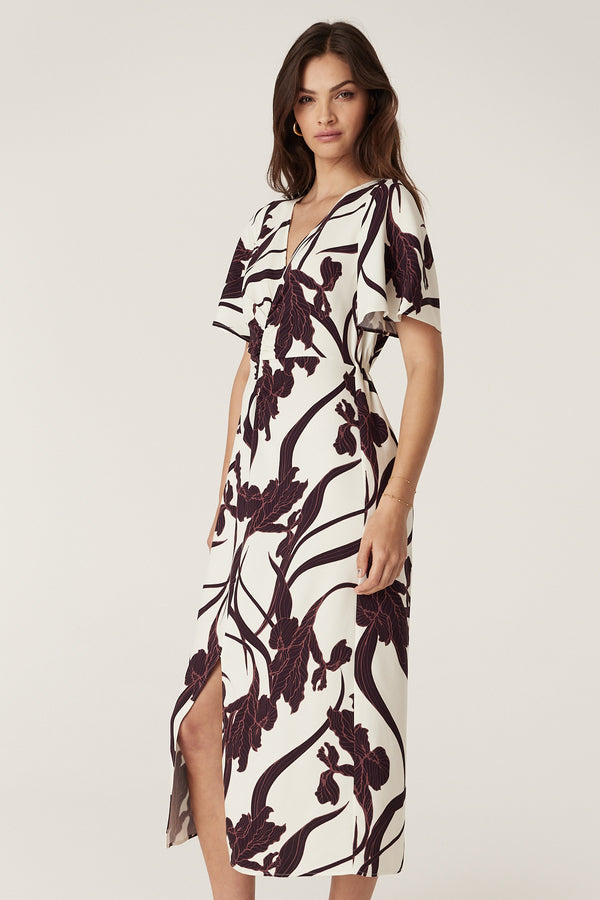 Woman in a relaxed fit Neve Dress with an exclusive iris print, V-neck, flared sleeves, and front split.