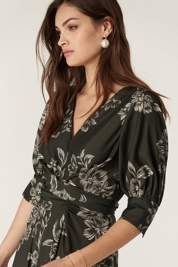 Dark green Holly Dress with white floral print, V-neck, wrap waist, and elbow sleeves.