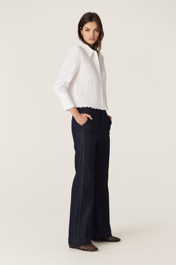 Model wears white May Shirt, 100% crisp cotton, with shirred front, long sleeves, and structured cuffs.