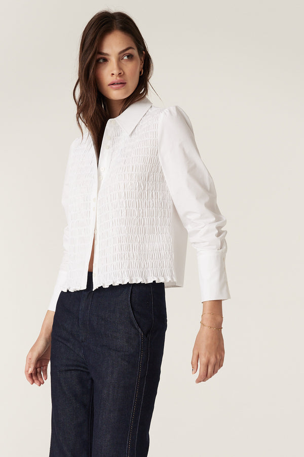 Woman wearing a white 100% cotton May Shirt with shirred front, long sleeves, and structured cuffs.