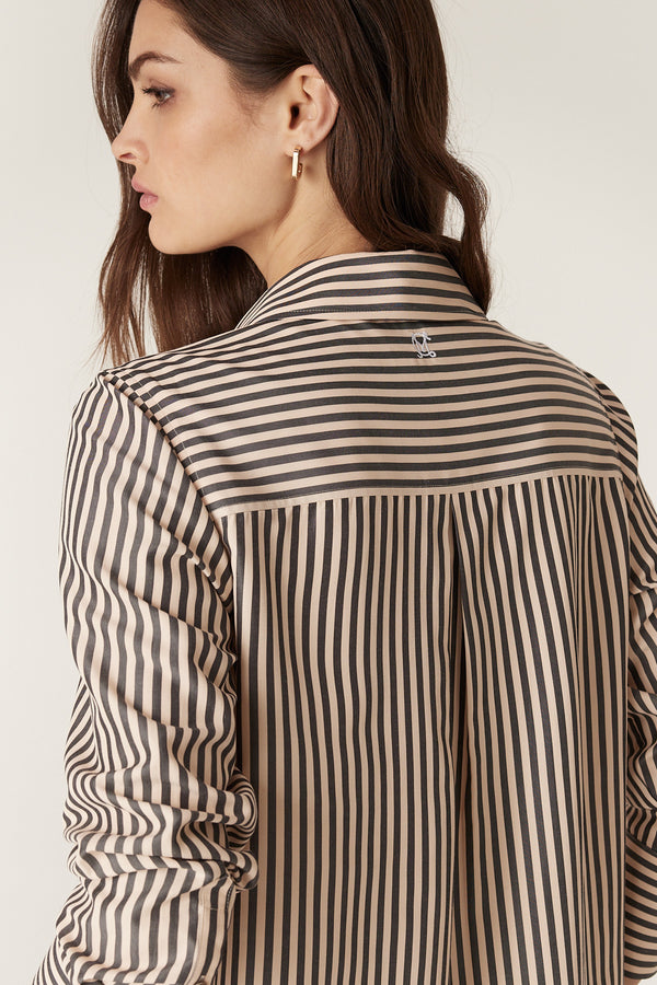 Woman wearing a khaki stripe Jamie shirt with a classic collar, button-through front, and curved hem.