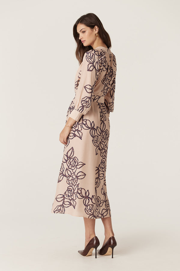 Woman in a beige silk blend Bloom Dress with a dark stencil floral print, stand collar, and raglan sleeves.