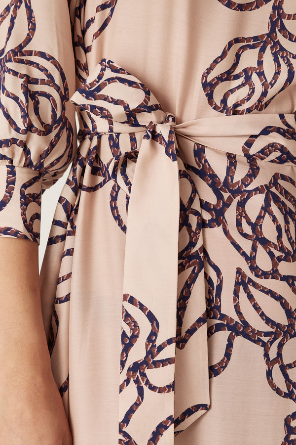 Close-up of a Bloom Dress in a light pink silk blend with a dark blue stencil floral print and matching waist tie.