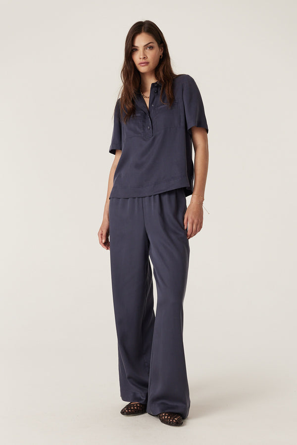 Woman in a relaxed navy Lyocell Ashton Blouse with half placket and front pockets, paired with matching pants.