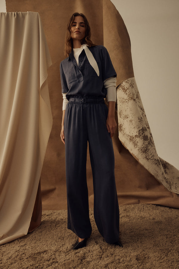 Model wears navy Lyocell Ashton Pant with elasticated waist, side pockets, and matching belt.