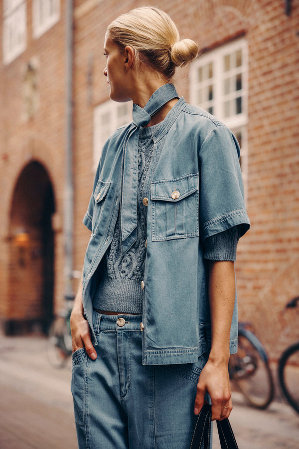 Woman in blue Pearce Top and matching pants, featuring utility pockets and contrast stitching.