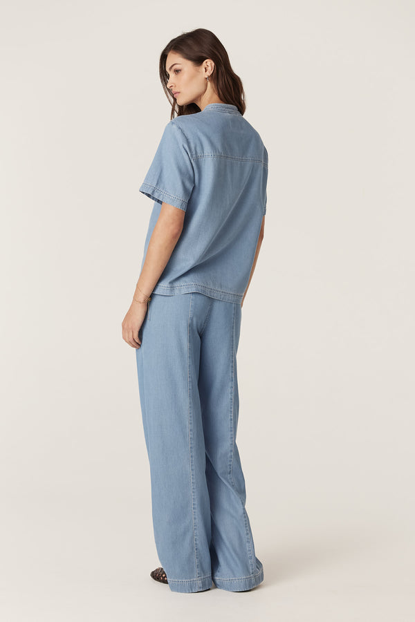 Woman in blue Pearce Top and matching pants, showing short sleeves, contrast stitching, and soft lyocell blend.