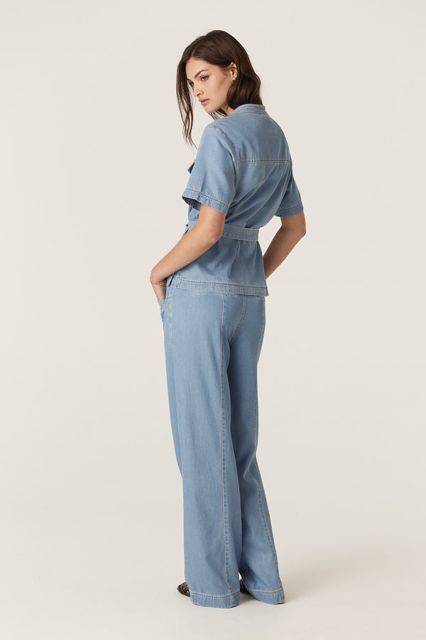Woman in blue lyocell-cotton Pearce Pant and matching top, featuring wide leg and belted waist.