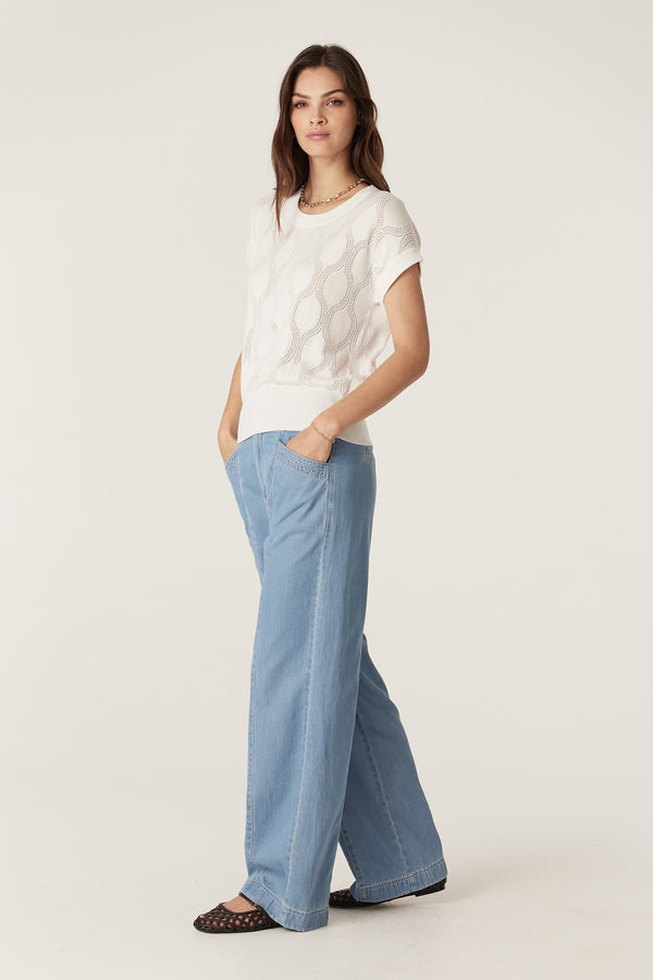 Model wearing blue Pearce wide-leg pants with double belt loops and a white knit top.