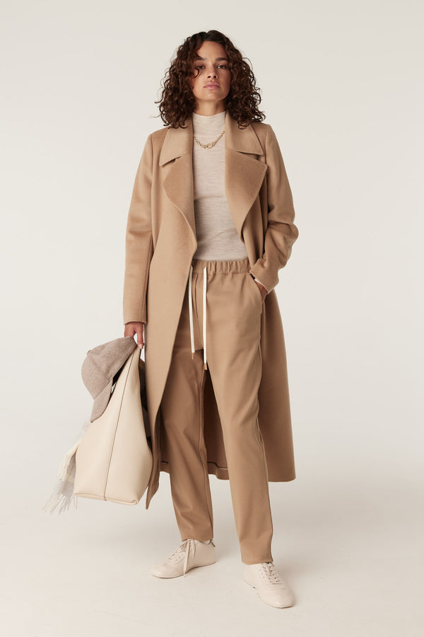 Camel Luca twill joggers with drawstring, paired with a matching coat, sweater, and cream accessories.