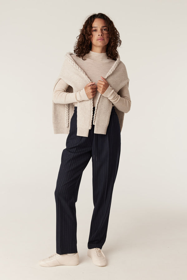 Woman wearing navy pinstripe Vincent wool blend pants with a relaxed fit, tapered leg, and elasticated waist.