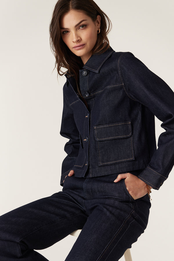 Woman wearing a dark indigo Burke denim jacket with contrast stitching and front pockets, paired with matching jeans.