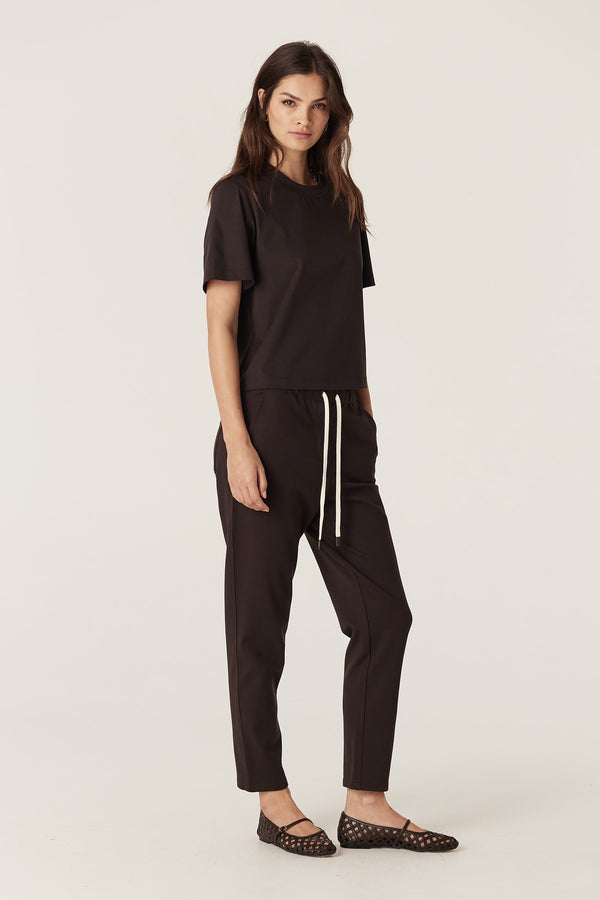 Woman wearing a relaxed fit espresso Pima Boxy Tee with matching pants and black woven flats.