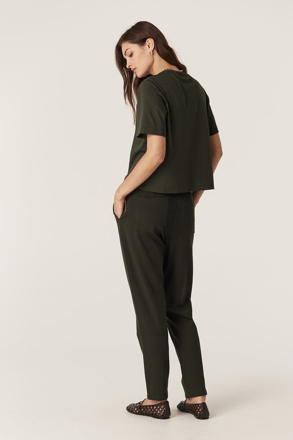 Woman in a relaxed fit forest green Pima cotton boxy tee and matching pants, hands in pockets.