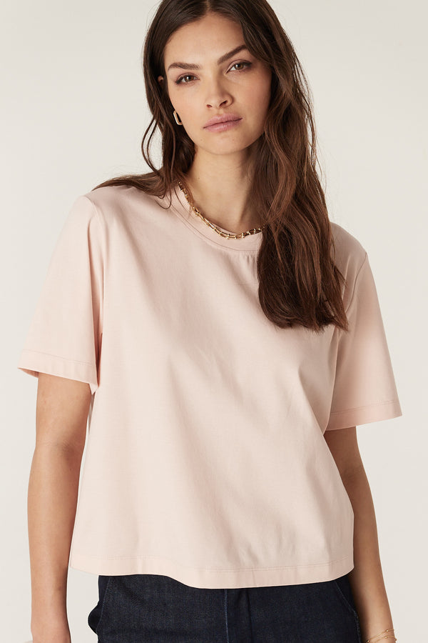 Model wearing a relaxed fit blush Pima cotton boxy tee with a ribbed crew neck and short sleeves.