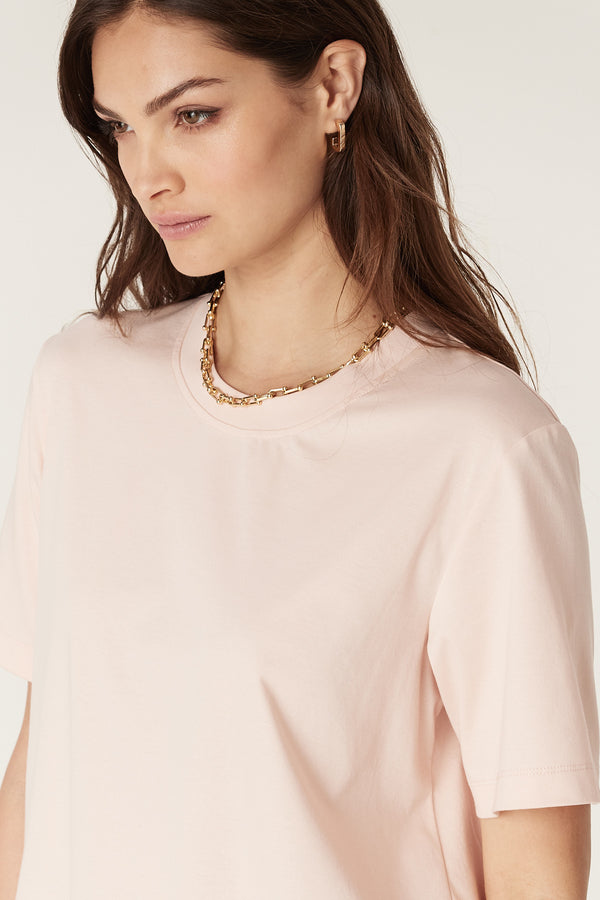 Woman wearing a blush Pima cotton boxy tee with a crew neck and short sleeves.