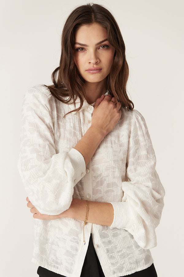 Woman in an ecru Vella Jacquard Blouse with soft sleeve gathers, buttoned cuffs, and shell buttons.