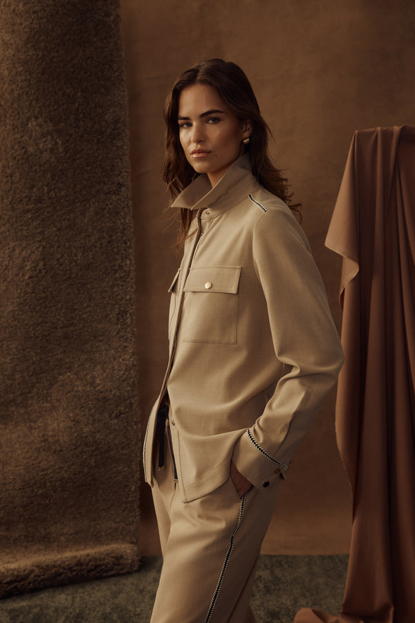 Model wears a camel Row Shirt with gold snaps, front pockets, and contrast braid trim.