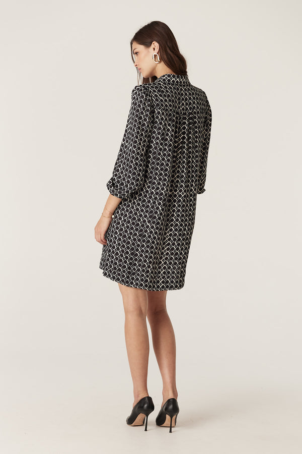 Model wearing a black geo print silk blend Hamilton dress with full sleeves and shirred cuffs.
