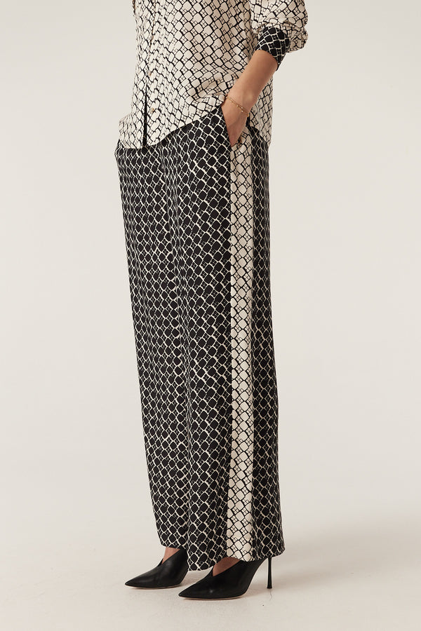 Black geo print Hamilton silk blend wide-leg pants with a cream side panel, worn with a matching top.