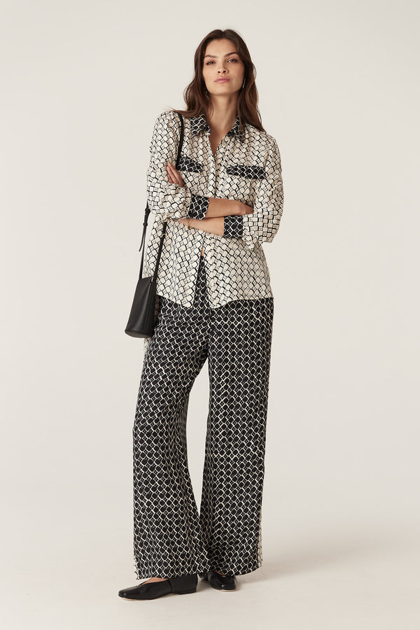 Woman in black and white geo print silk blend Hamilton Pant with wide leg and matching blouse.