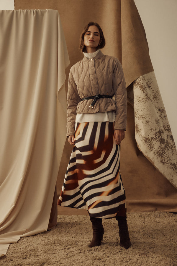 Model wears a bias-cut Sasha Zebra print skirt, quilted jacket, and boots.