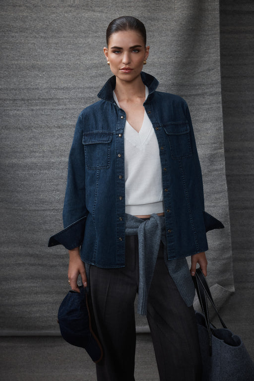 Model in an indigo Dallas denim shirt with patch pockets, cream snaps, over a white top and grey pants.