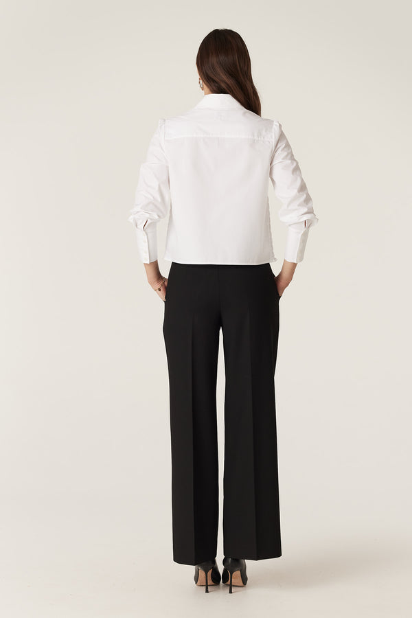 Model from behind wearing black Evie wide leg pants with a high waistband and front patch pockets.