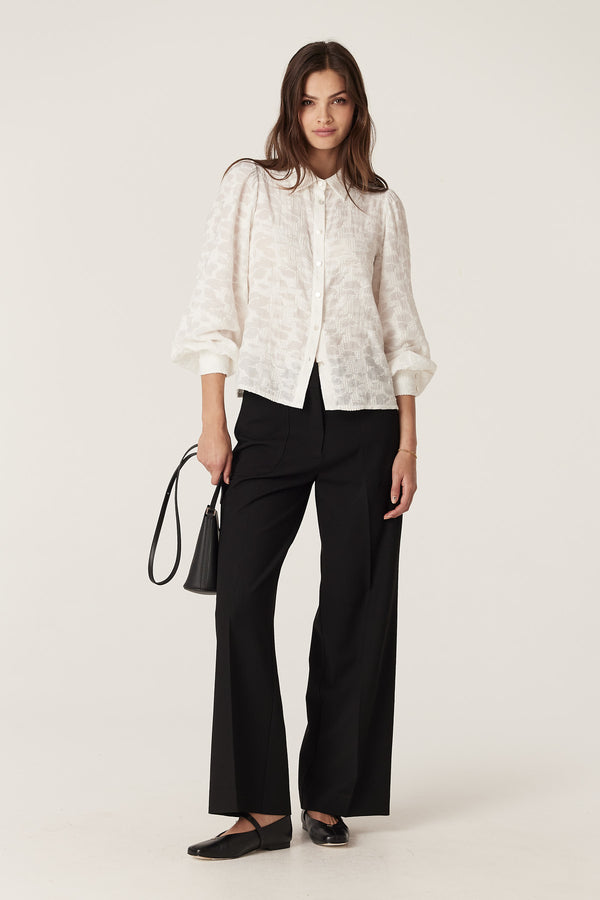 Model wears black Evie wide leg pants with a high waist, front patch pockets, and a white blouse.