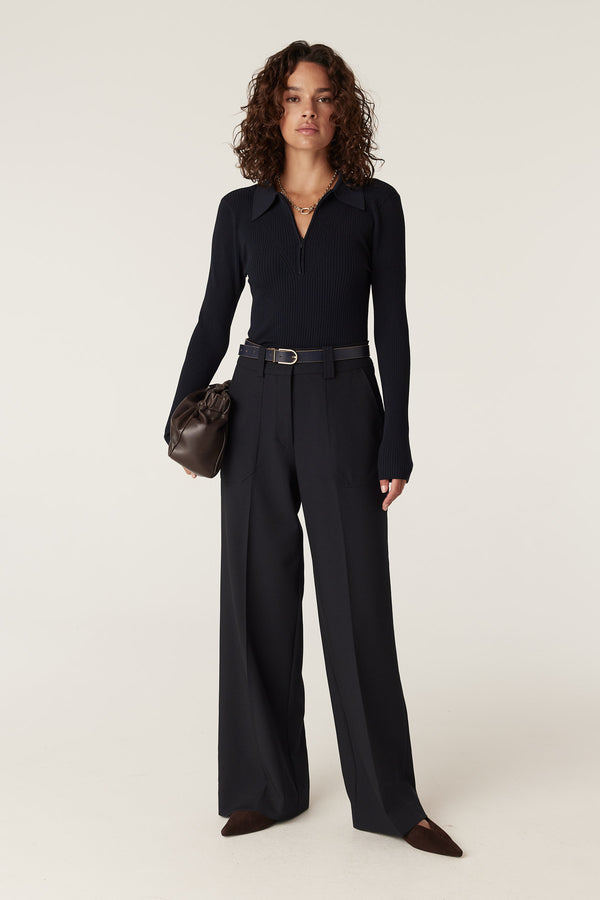 Woman in navy Evie wide leg pants with front patch pockets, a dark belt, and a black long-sleeve top.