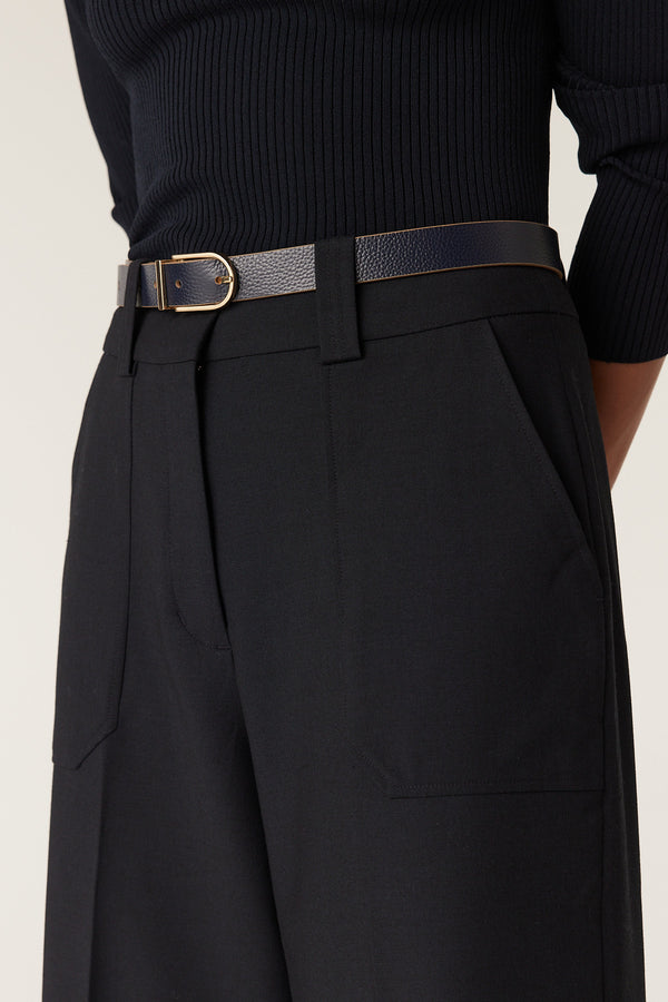 Navy Evie wide leg pants with a high fixed waistband, fly front, and front patch pockets, styled with a thin navy belt.