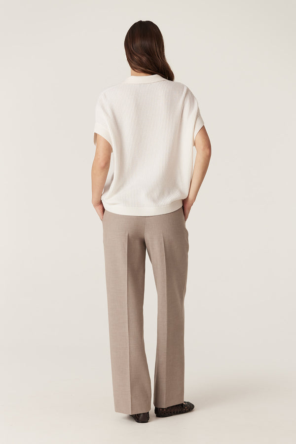 Model from behind wearing fawn Evie wide leg pants with a high fixed waistband and front patch pockets.