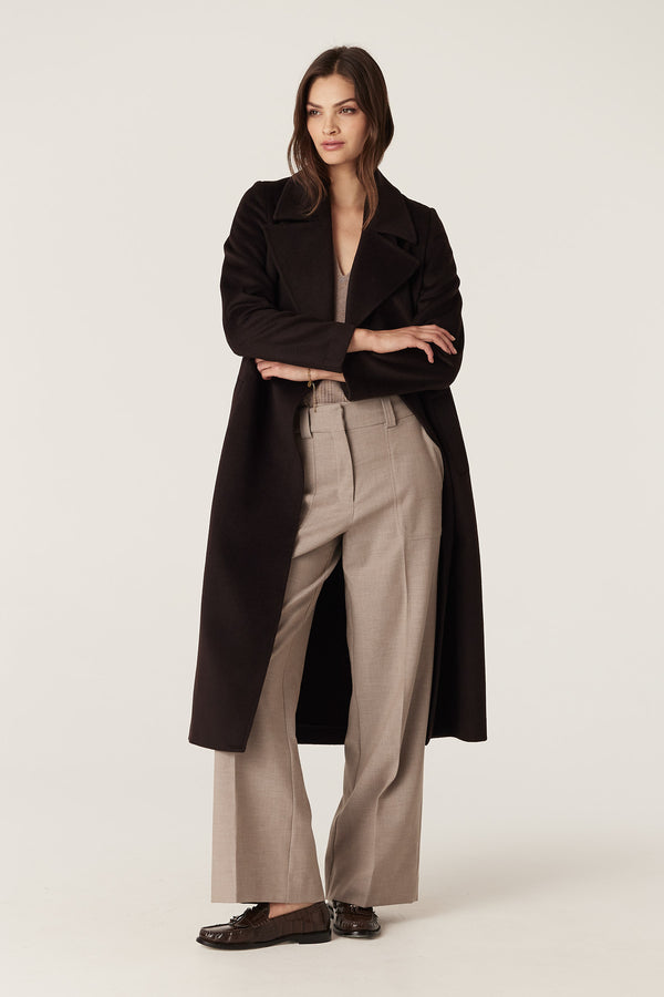 Model wearing fawn Evie wide leg pants with a high waist, front patch pockets, and a dark coat.
