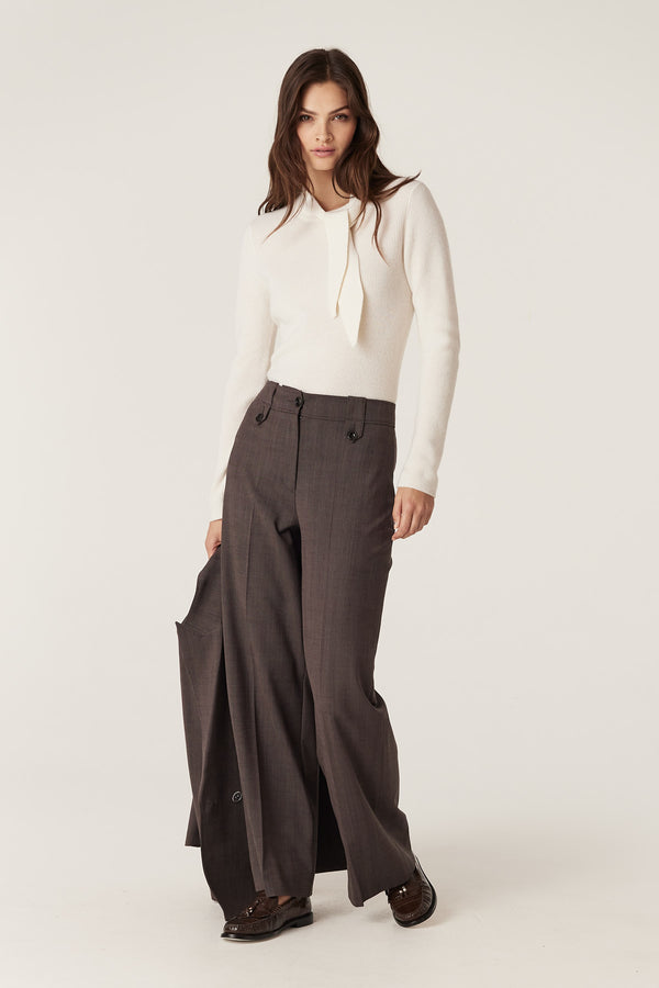 Model wears mocha Fletcher Wool Pant with wide leg, high waist, and tab belt loops, holding a matching blazer.