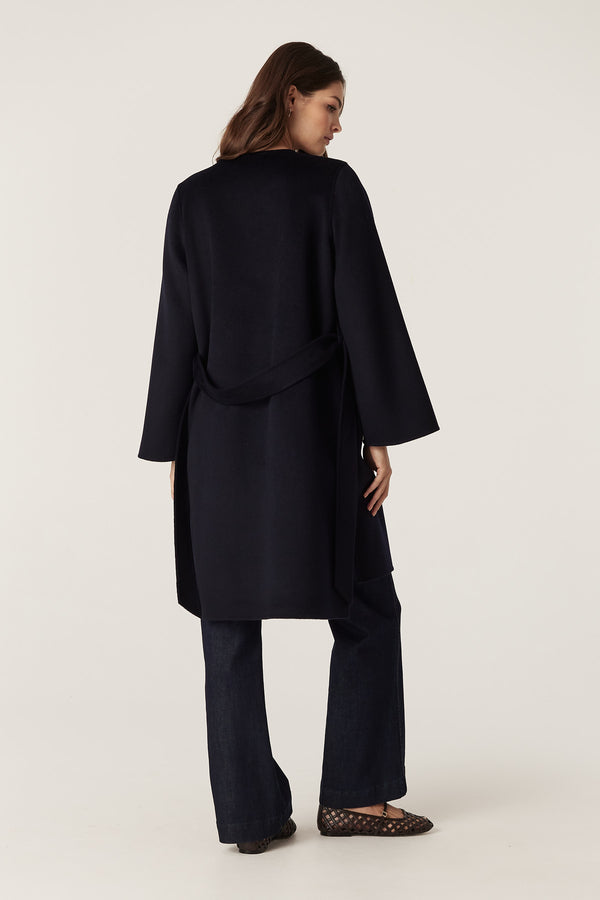 Woman from behind wearing a navy Lawson wool coat with flared sleeves, high-low hem, and matching belt.