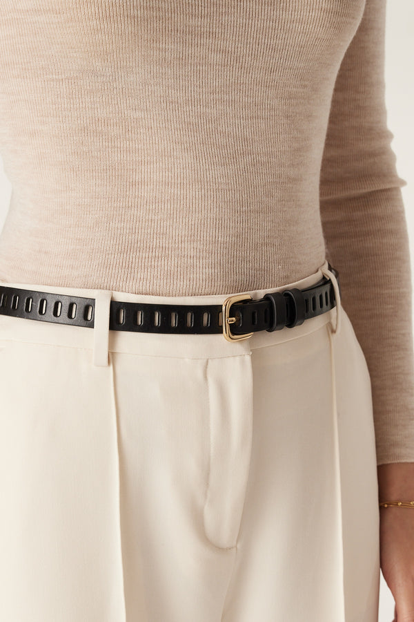 Black Fay leather belt with multiple eyelets and gold buckle, worn with beige top and cream trousers.