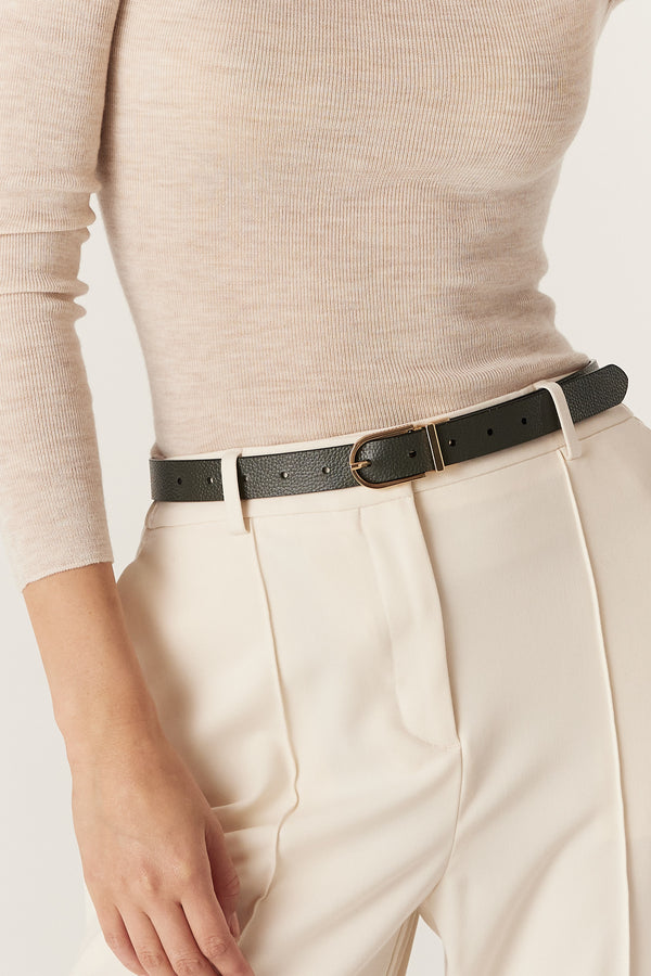 Black genuine leather reversible belt with a gold buckle, worn with cream pants.