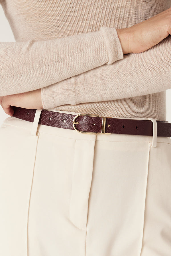 Genuine leather reversible belt in port, 2.5cm wide, with a gold hardware buckle, worn with ecru trousers.