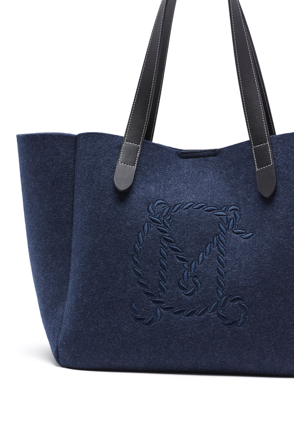 Indigo marle wool blend felt travel tote with black leather handles and embroidered rope-style M logo.