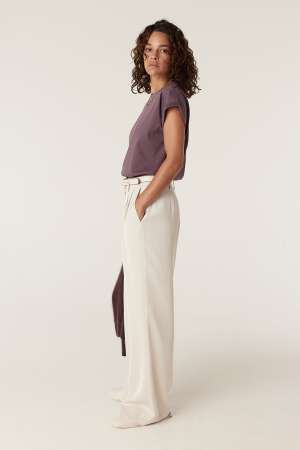 Woman wearing a berry Pima tee with cap sleeves, cream wide-leg pants, and a white belt.