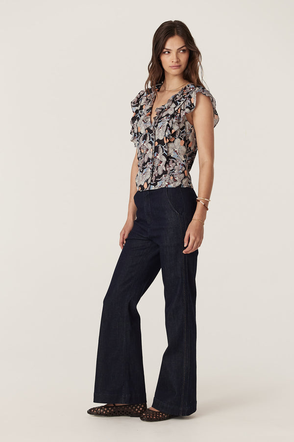 Woman wearing a Leigh Frill Top in Orchid Print, a silk blend V-neck top with frill details and self-fabric buttons.