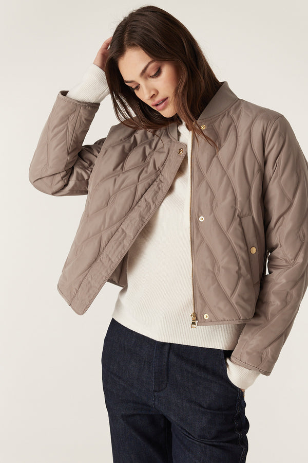 Woman in fawn Martina Puffer jacket with quilted cable design, rib collar, and gold hardware.