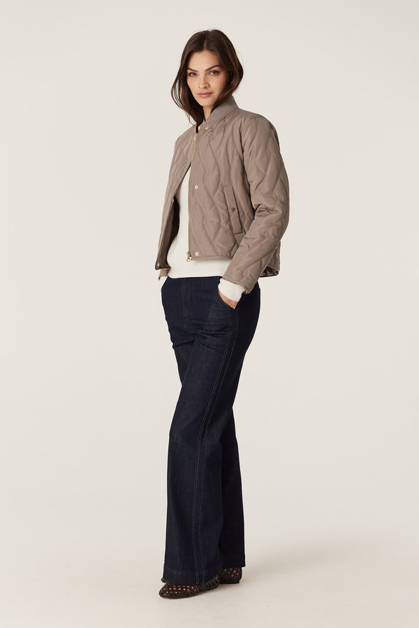 Woman in fawn Martina Puffer jacket with quilted cable design, rib collar, and front pockets.