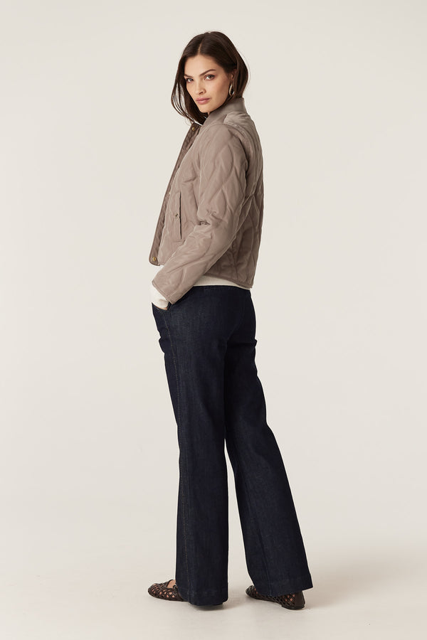 Woman in fawn Martina Puffer jacket with quilted cable design, rib collar, and front pockets.