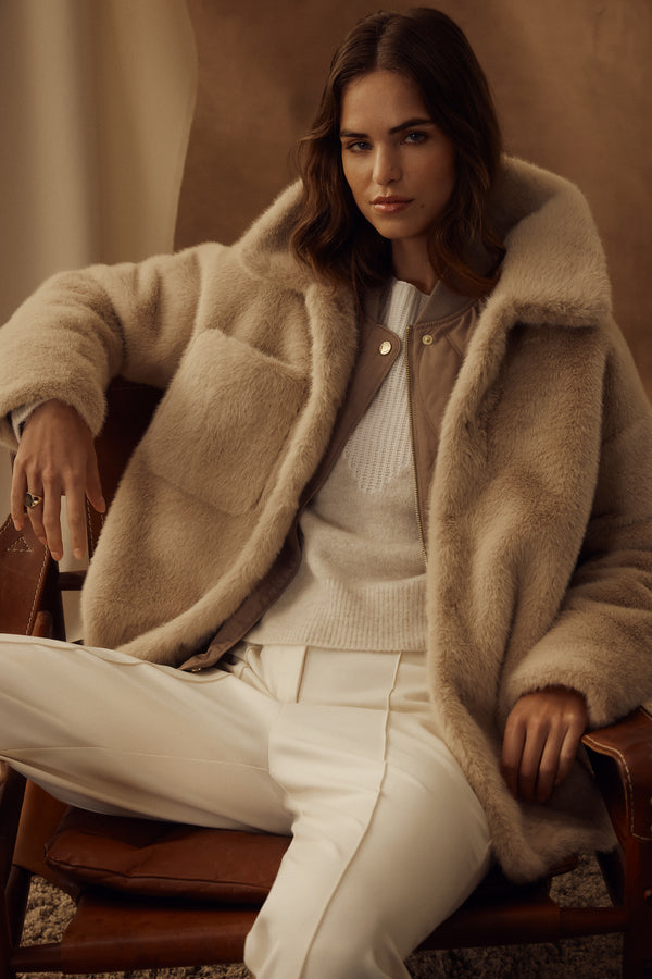 Franzi camel faux fur jacket with wide collar, worn over a quilted vest and white sweater.