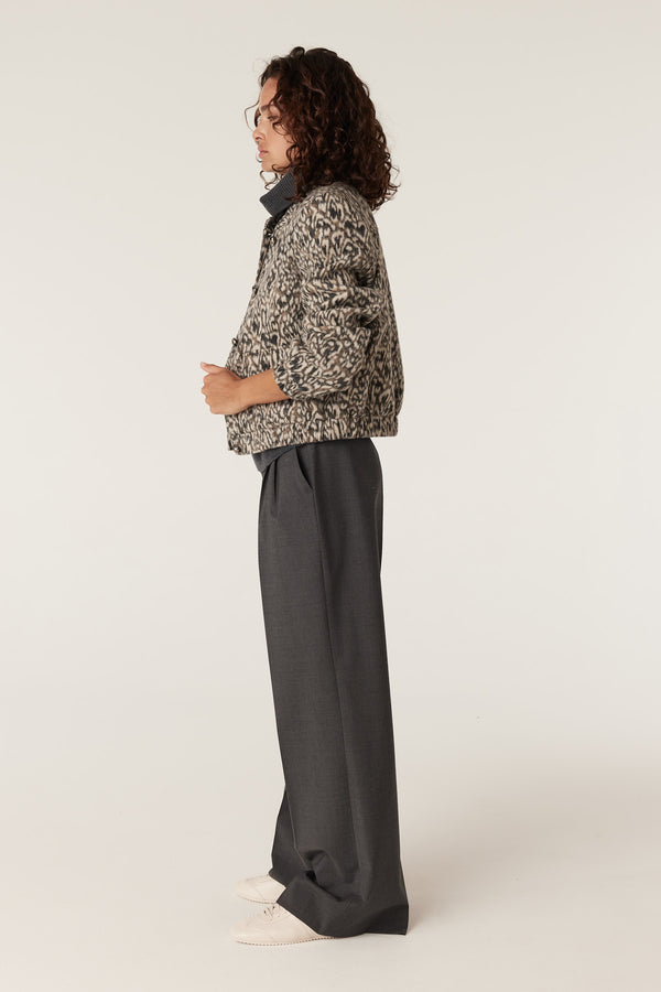 Woman in Heike Animal print jacket with dark collar, paired with grey wide-leg trousers and white shoes.